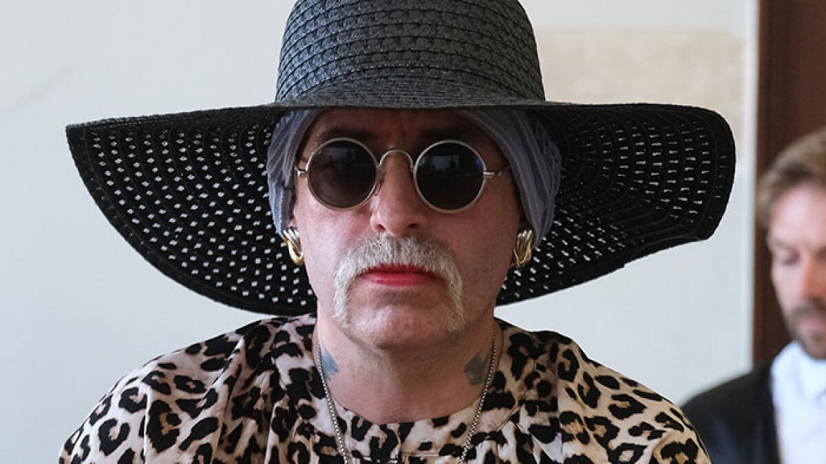 Radical right-winger wearing sunglasses and a large hat after gender change, preparing to serve sentence in women's jail.