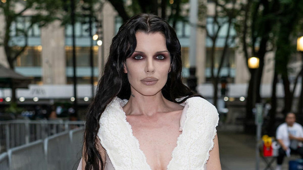 Julia Fox with dark makeup and wavy hair attending an outdoor event, reflecting on her plastic surgeries regrets.