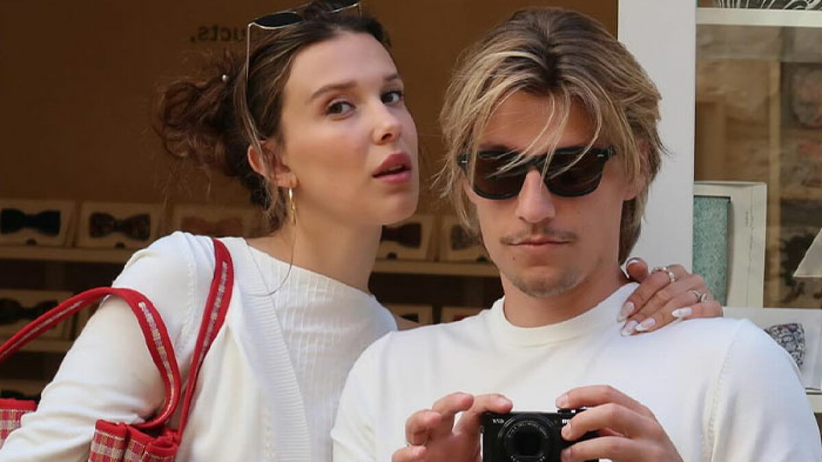 Millie Bobby Brown and Jake Bongiovi together in public, posing closely while capturing a photo during daytime outing.