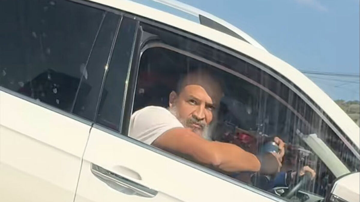 Man in white shirt inside white car involved in road rage coffee toss incident captured in viral video.