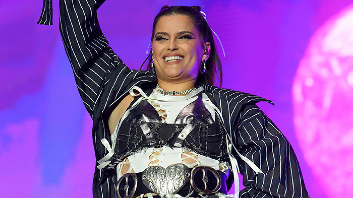 Nelly Furtado onstage wearing a racy top and miniskirt, confidently showing off her natural curves during a live performance.