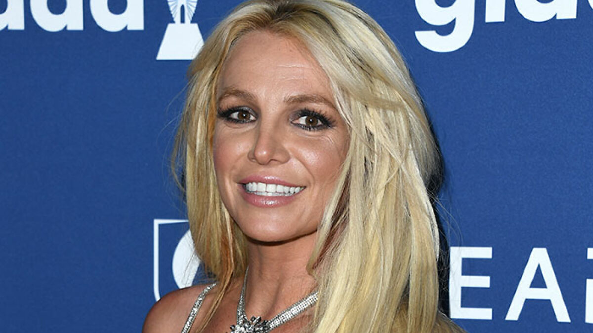 Britney Spears smiling at event with long blonde hair, showcasing figure and glamour amid mental help concerns.