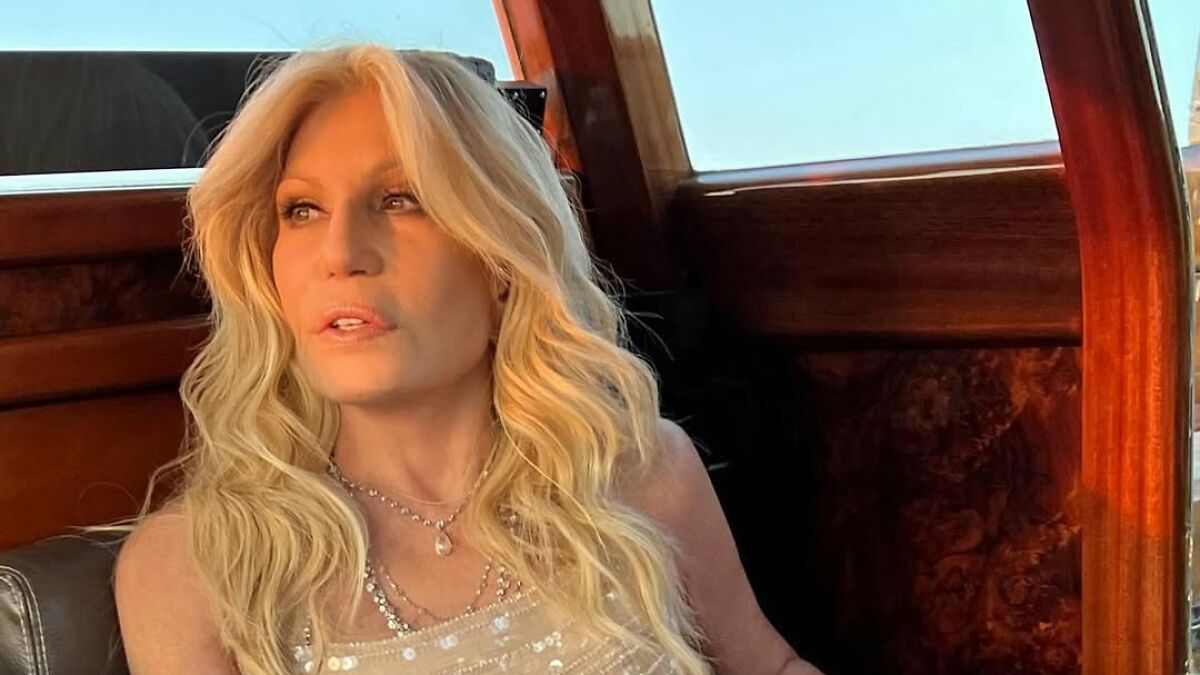 Donatella Versace with wavy blonde hair wearing a sequined top, showing a stunning youthful transformation on a boat.