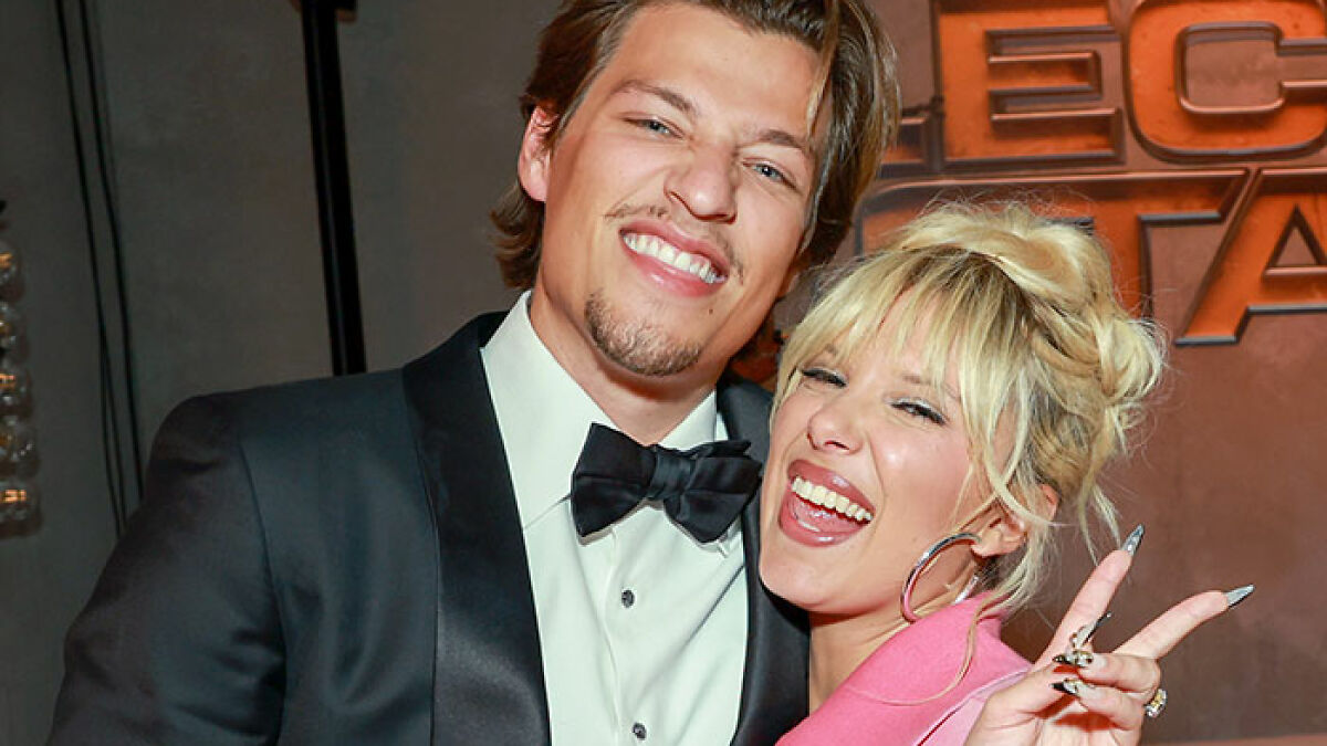 Two smiling people posing together at an event, highlighting Millie Bobby Brown adoption and fan worries.