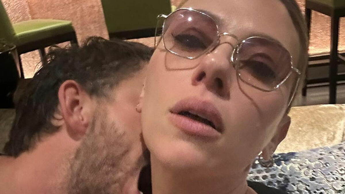 Jonathan Bailey and Scarlett Johansson in a racy selfie sparking heated reactions, close-up with sunglasses indoors.