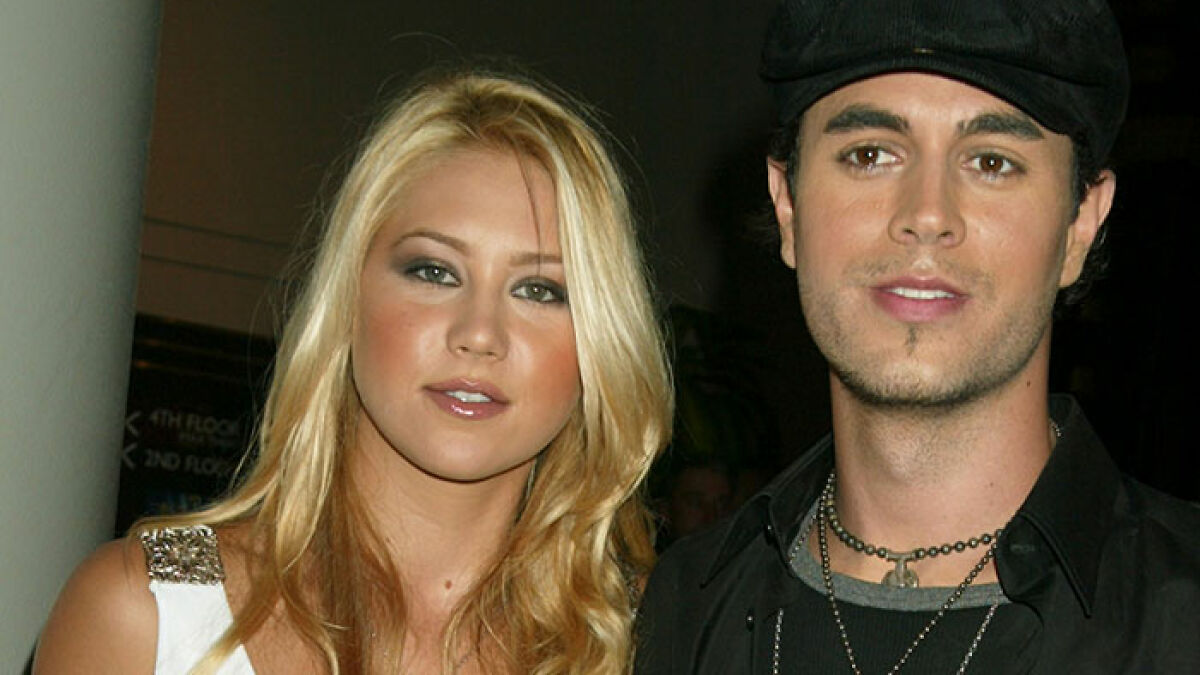 Anna Kournikova and Enrique Iglesias posing together in a dimly lit setting, highlighting their longtime partnership.