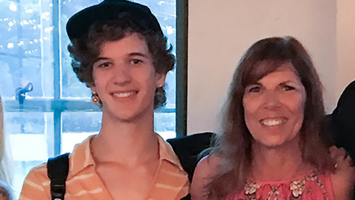 Young man wearing cap and striped shirt standing next to woman with floral top in a well-lit indoor setting