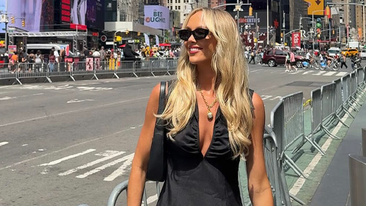 Blonde woman with sunglasses smiling in black dress on busy city street, related to woman who slept with 583 men topic.
