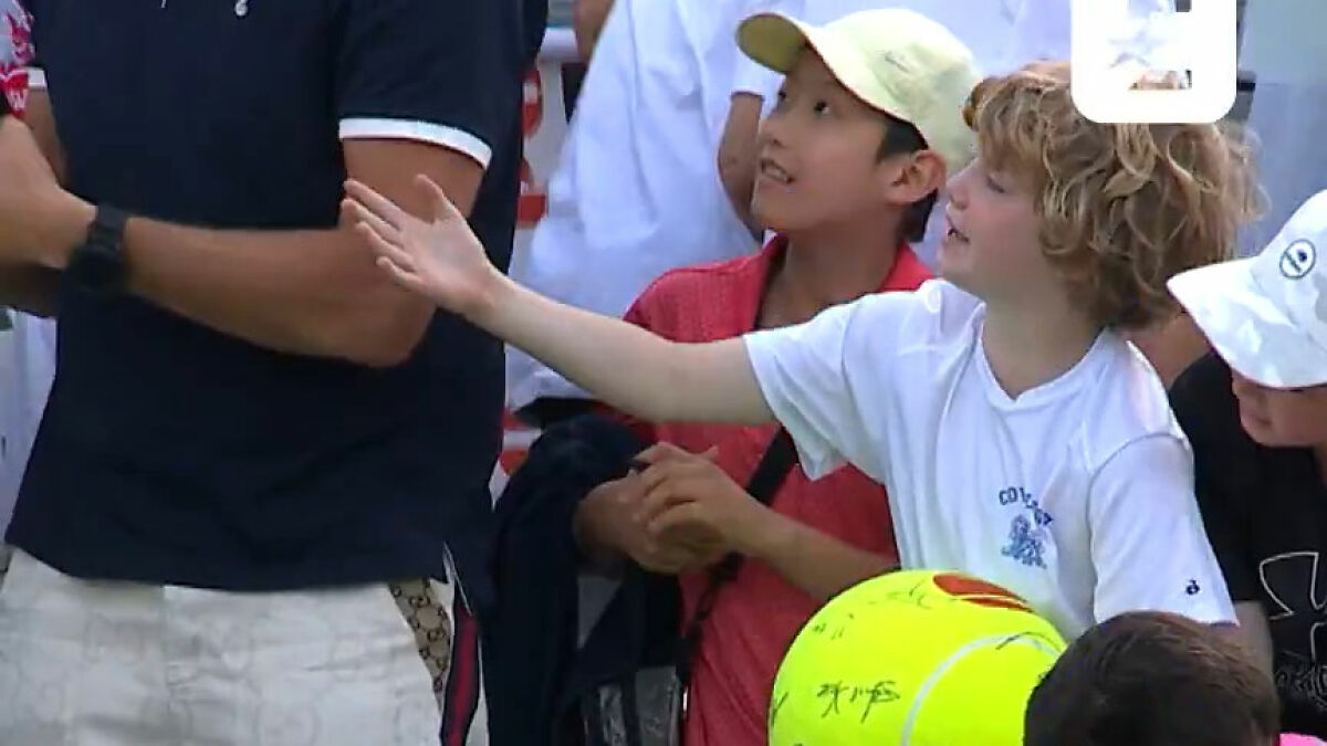 Young tennis fan reaching out as man snatches Kamil Majchrzak's hat during viral US Open moment with signed tennis ball nearby