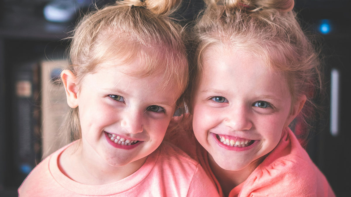 Two young girls smiling happily, illustrating the impact of lifelong pain caused by horrible names.