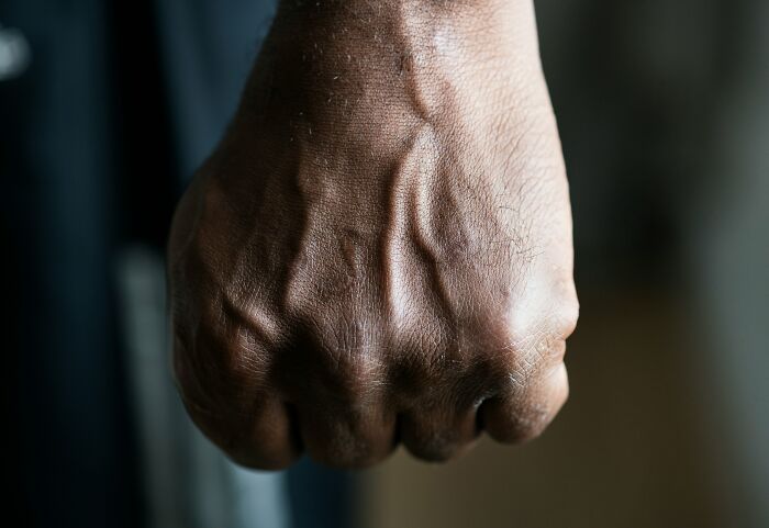 Close-up of a clenched fist representing frustration with gender-based double standards in society.