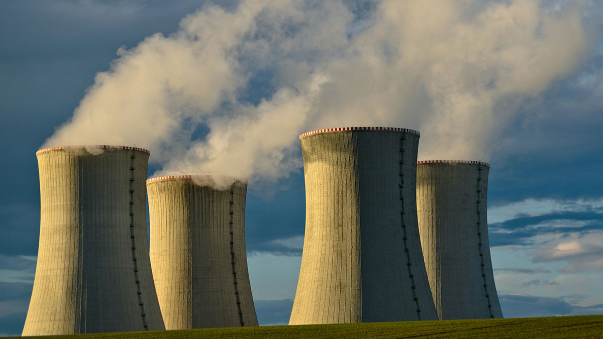 Cooling towers of a nuclear power plant emitting steam under a cloudy sky, representing totally safe things people fear.