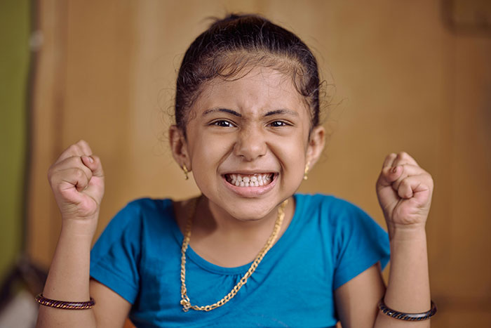 Angry young girl clenching fists, reflecting frustration over stepdad suggesting punishment for using native language. Angry young girl clenching fists, reflecting frustration over stepdad suggesting punishment for using native language.