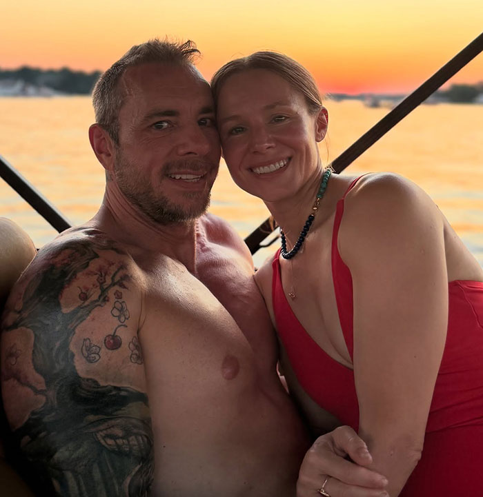 Dax Shepard smiling shirtless next to Heidi Klum in a red dress enjoying a sunset moment on the water. Dax Shepard smiling shirtless next to Heidi Klum in a red dress enjoying a sunset moment on the water.