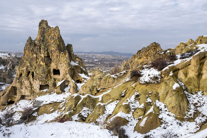 Ancient underground city carved into rocky terrain covered with snow, showcasing mysterious multi-level hidden dwellings. Ancient underground city carved into rocky terrain covered with snow, showcasing mysterious multi-level hidden dwellings.