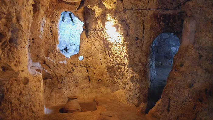 Ancient carved underground city passage illuminated with pottery, showcasing mysterious tunnels and stone walls deep beneath the surface. Ancient carved underground city passage illuminated with pottery, showcasing mysterious tunnels and stone walls deep beneath the surface.