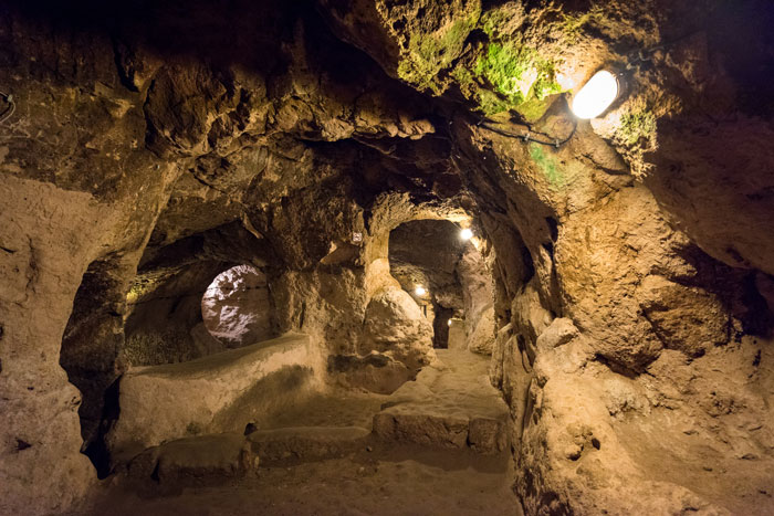 Underground city tunnels with carved rock walls illuminated by lights, showcasing mysterious 18-story deep ancient passageways. Underground city tunnels with carved rock walls illuminated by lights, showcasing mysterious 18-story deep ancient passageways.