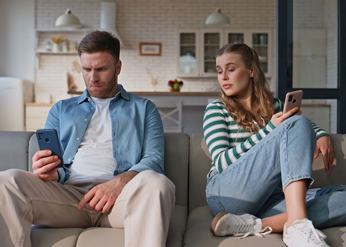 A man and woman on a couch looking upset at their phones, highlighting disgusting things people discovered about friends.