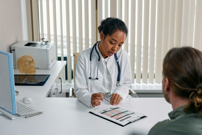Doctor reviewing medical charts with patient in office, illustrating people who found out something disgusting about a friend.