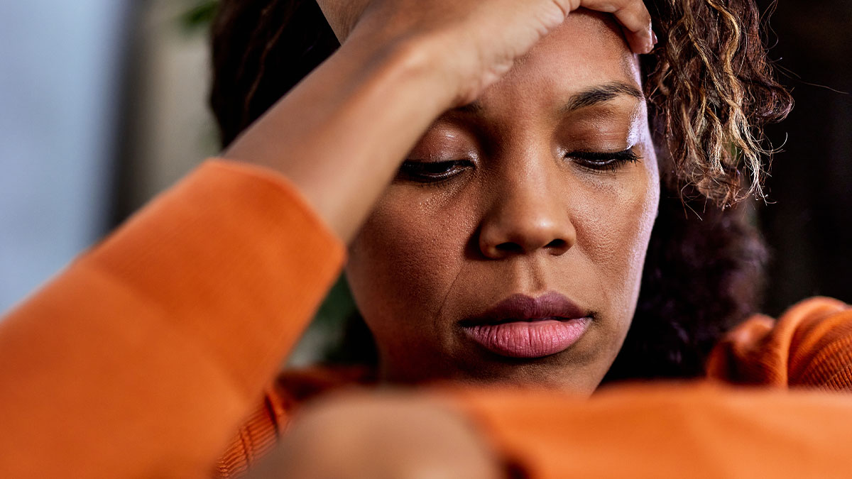 Woman in orange sweater looking distressed, reflecting the emotional impact of divorce and family truth revelations.
