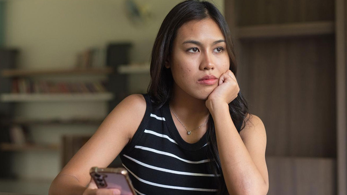 Woman looking concerned and holding phone, representing lady dragging shameless ex to court over house dispute.