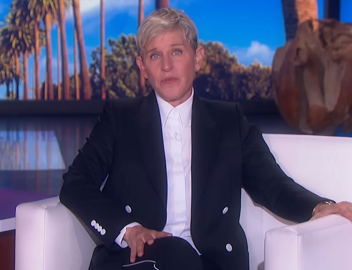 Ellen DeGeneres seated on a white couch during a TV show amid bullying controversy and new claims from former staff.