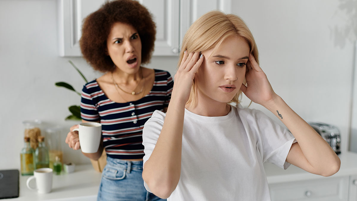 Young woman upset as cousin refuses to babysit instead of attending school, causing tension in the kitchen.