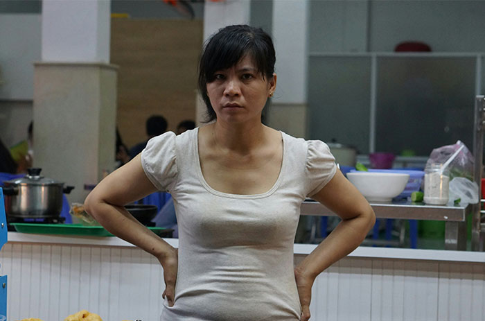 Woman with arms on hips in a kitchen setting, representing a social media roasting threat to a bakery over a refund dispute.