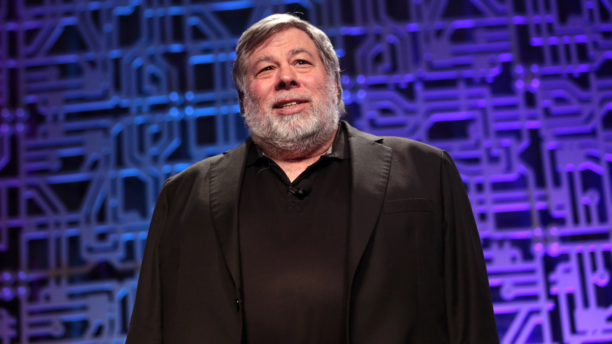 Inventor presenting on stage with a circuit board background, representing everyday inventions and brilliant minds.