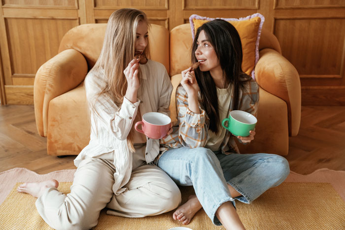 Two women sitting on the floor eating cookies with mugs, illustrating betrayal and giving an ex-best friend a taste of her own medicine. Two women sitting on the floor eating cookies with mugs, illustrating betrayal and giving an ex-best friend a taste of her own medicine.