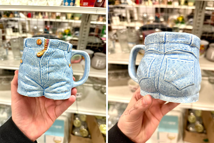 Hand holding a blue ceramic mug shaped like denim shorts, a unique thrift store find in a store aisle.