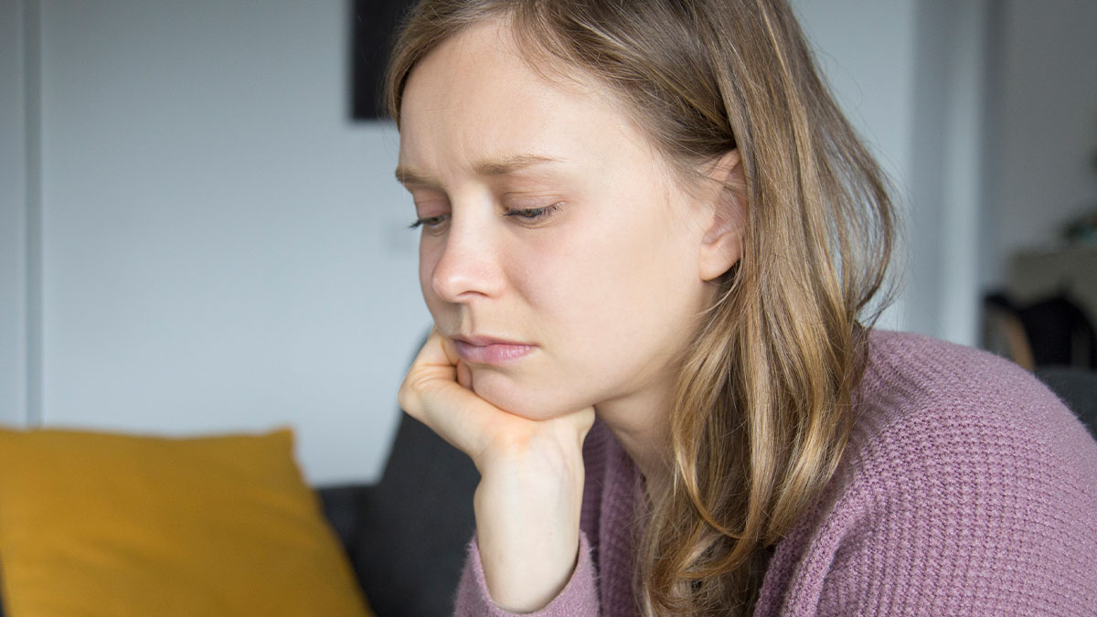 Woman looking upset and thoughtful at home, reflecting on family demands and financial conflicts with her sister.