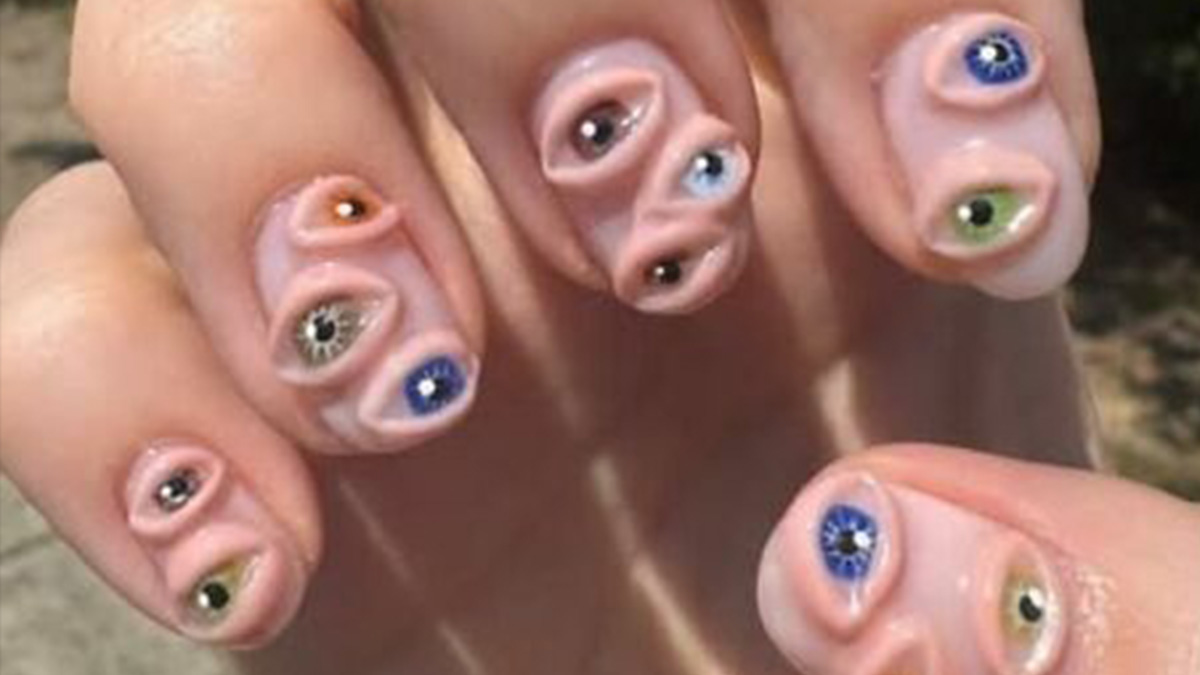Fingernails with a bizarre DIY craft showing multiple realistic eyes painted or attached, highlighting craft shaming.