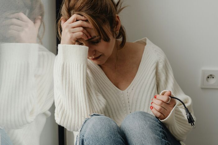 Woman sitting on the floor stressed, holding a power plug, symbolizing emotional struggle with fiance non biological child wedding issues. Woman sitting on the floor stressed, holding a power plug, symbolizing emotional struggle with fiance non biological child wedding issues.