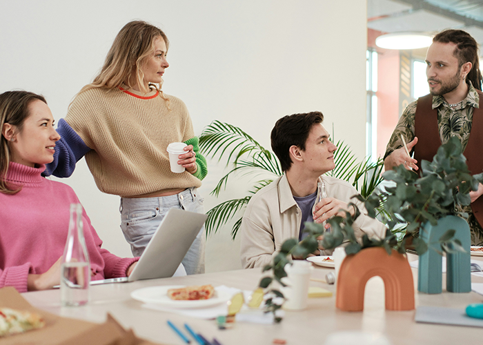 Team discussing work issues around a table in an office, highlighting challenges with banning flexible hours policy. Team discussing work issues around a table in an office, highlighting challenges with banning flexible hours policy.