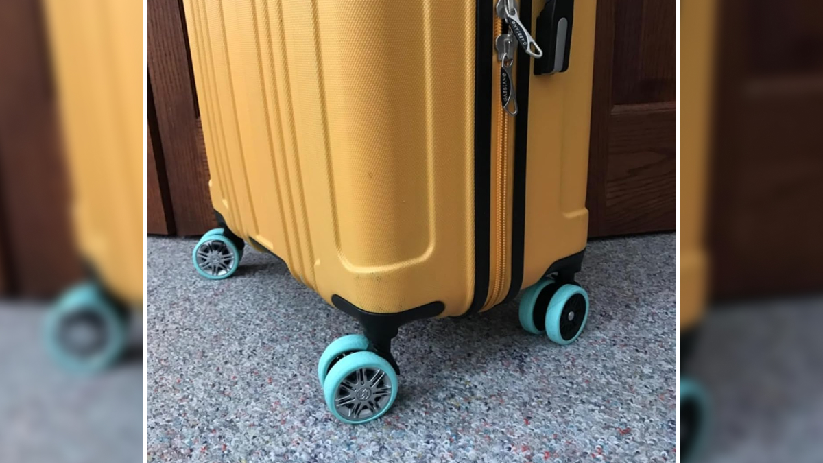 Yellow hard-shell suitcase with teal spinner wheels on carpeted floor for hassle-free travel essentials.