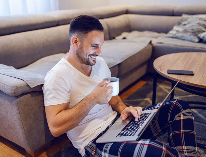 Grieving employee working on laptop at home, drinking coffee, showing resilience despite difficult boss behavior. Grieving employee working on laptop at home, drinking coffee, showing resilience despite difficult boss behavior.