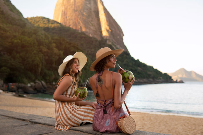 Two women enjoying a beach view, sipping coconuts, capturing the theme of woman wants friends to bend for travel needs. Two women enjoying a beach view, sipping coconuts, capturing the theme of woman wants friends to bend for travel needs.