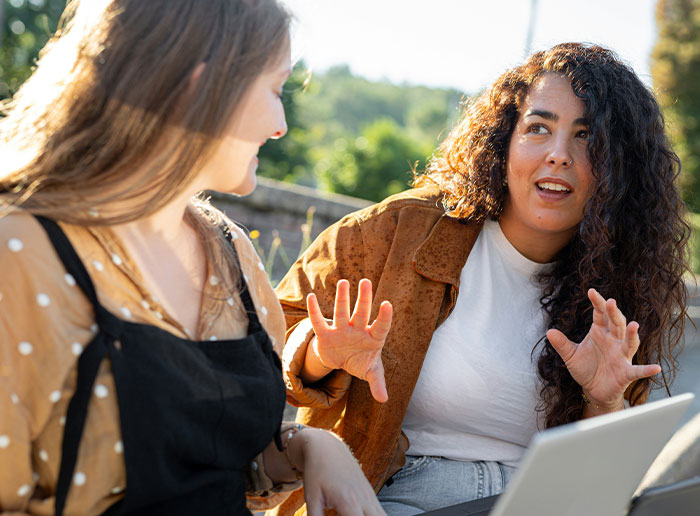 Teen friends having a serious conversation outdoors during the day, one looking confused and the other explaining something. Teen friends having a serious conversation outdoors during the day, one looking confused and the other explaining something.
