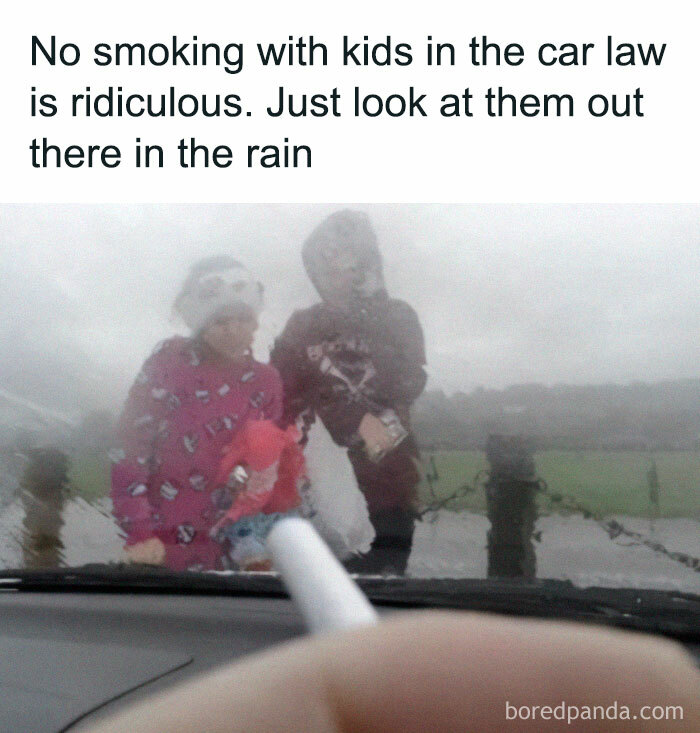 Blurred photo through a rain-covered car window showing people outside and a meme about British smoking laws and kids in the rain.
