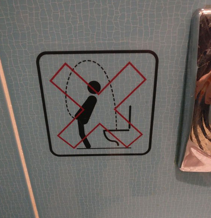 Warning sign on bathroom wall showing a stick figure urinating into a toilet with a red X, illustrating funny ways people learned their lesson.
