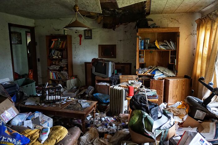 Cluttered and filthy living room filled with trash and broken furniture, illustrating gross and unexpected home conditions.