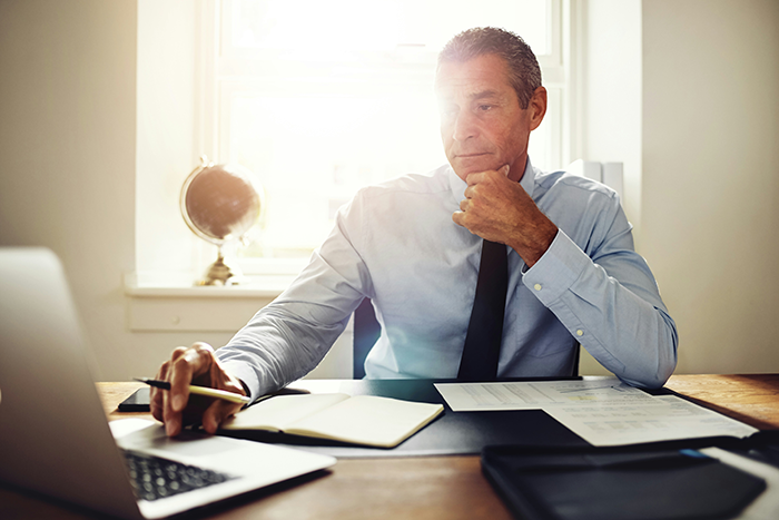 Man in office preparing to teach 12 years worth of knowledge before his PTO while working on laptop at desk. Man in office preparing to teach 12 years worth of knowledge before his PTO while working on laptop at desk.