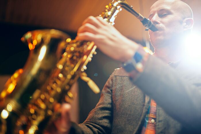 Man playing a saxophone with warm lighting, illustrating ingenious inventions that found new purposes over the years