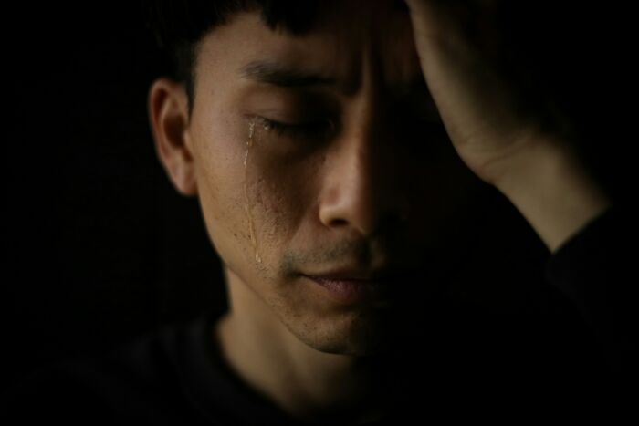 Close-up of a man with a tear rolling down his cheek, expressing emotion related to gender-based double standards.