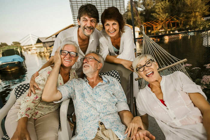 Group of happy older adults enjoying time together by the water, highlighting gender-based double standards in social settings.