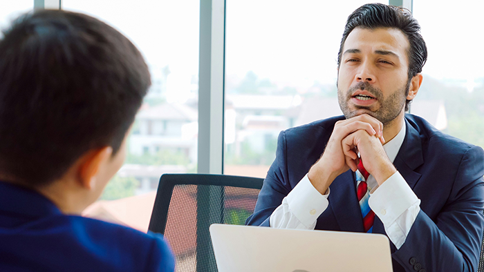 Man in a suit discussing work with colleague, symbolizing a guy expected to teach years of knowledge before PTO. Man in a suit discussing work with colleague, symbolizing a guy expected to teach years of knowledge before PTO.