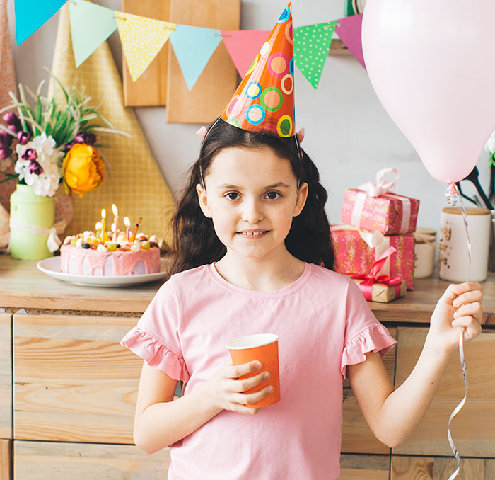 Young girl at birthday party with balloon and cup, showing kindness after being bullied over party seat. Young girl at birthday party with balloon and cup, showing kindness after being bullied over party seat.