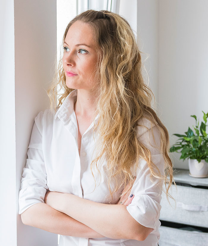 Young woman with blonde hair looking thoughtful near window, depicting girl bullied over party seat and kindness lesson. Young woman with blonde hair looking thoughtful near window, depicting girl bullied over party seat and kindness lesson.