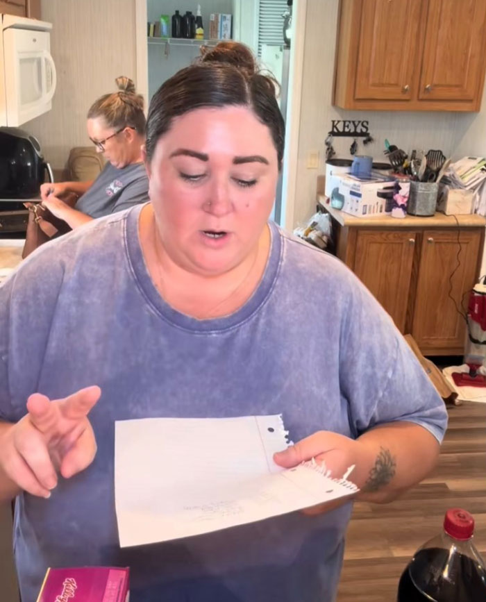 Woman in a kitchen reviewing a grocery list as part of an American family grocery haul with cereal and soda nearby. Woman in a kitchen reviewing a grocery list as part of an American family grocery haul with cereal and soda nearby.